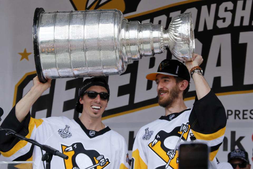 FILE - In this Wednesday, June 14, 2017, file photo, Pittsburgh Penguins goalies Marc-Andre Fleury, left, and Matt Murray hold the Stanley Cup on stage after riding in the Stanley Cup victory parade in Pittsburgh. Managing top goaltenders’ schedules is the NHL’s version of load management. Each of the past five Stanley Cup-winning goalies started fewer than 60 games in the regular season, along with three of the past five runners up. (AP Photo/Gene J. Puskar, File)