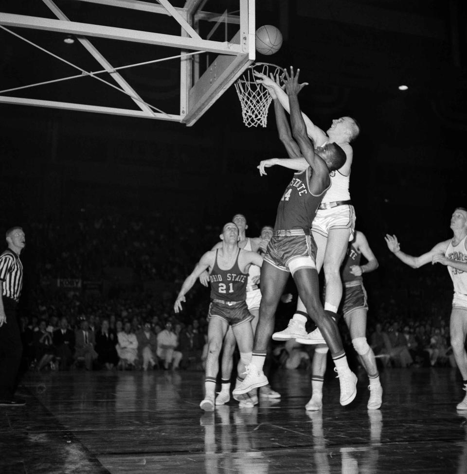 In this March 19, 1960 , photo, California forward Bill McClintock, center right, tips the ball in for two points against Ohio State forward Joe Roberts (14) in the second half of an NCAA final in the Cow Palace, San Francisco, Calif. At left is Ohio State guard Larry Siegfried.