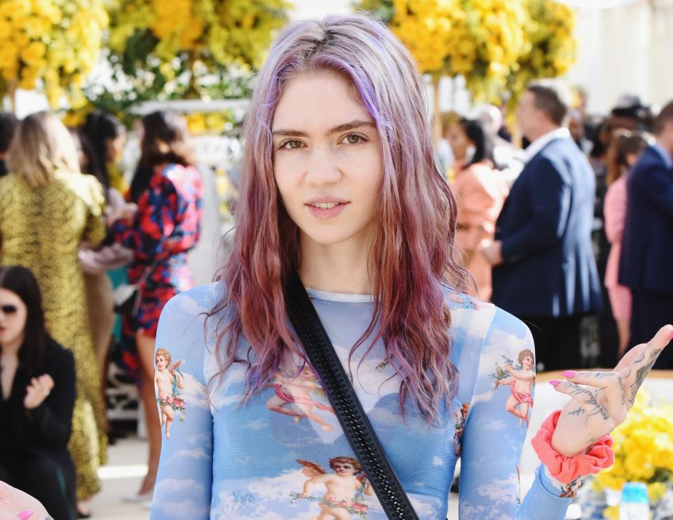 Grimes wears a sheer blue top with angels printed on it