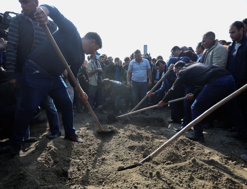 Mourners attend a funeral following recent shelling in Garayusifli