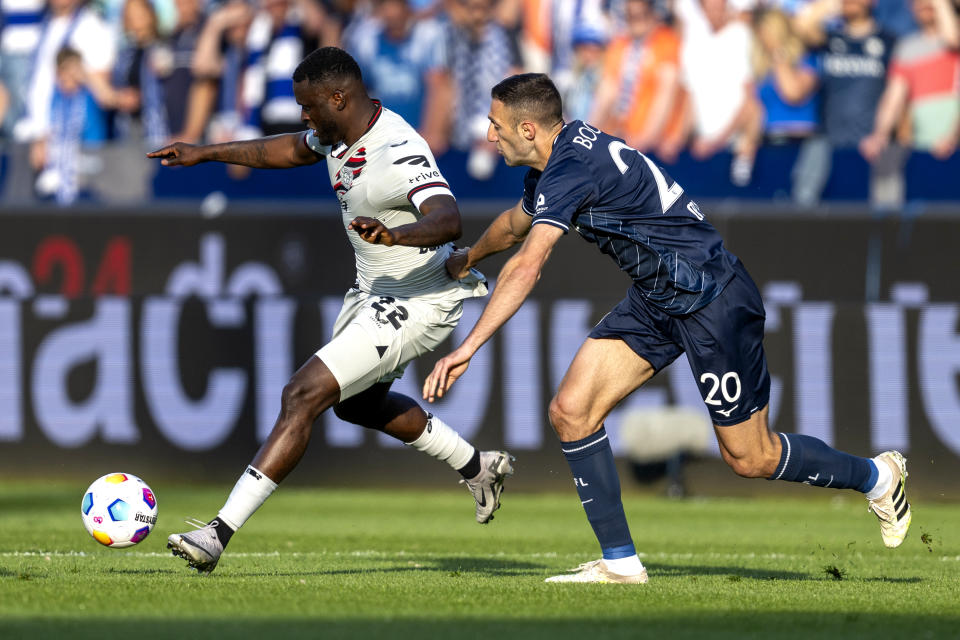 Leverkusen's Victor Boniface, left, and Bochum's Ivan Ordets, right, challenge for the ball during the German Bundesliga soccer match between VfL Bochum and Bayer 04 Leverkusen in Bochum, Germany, Sunday, May 12, 2024. (David Inderlied/dpa via AP)