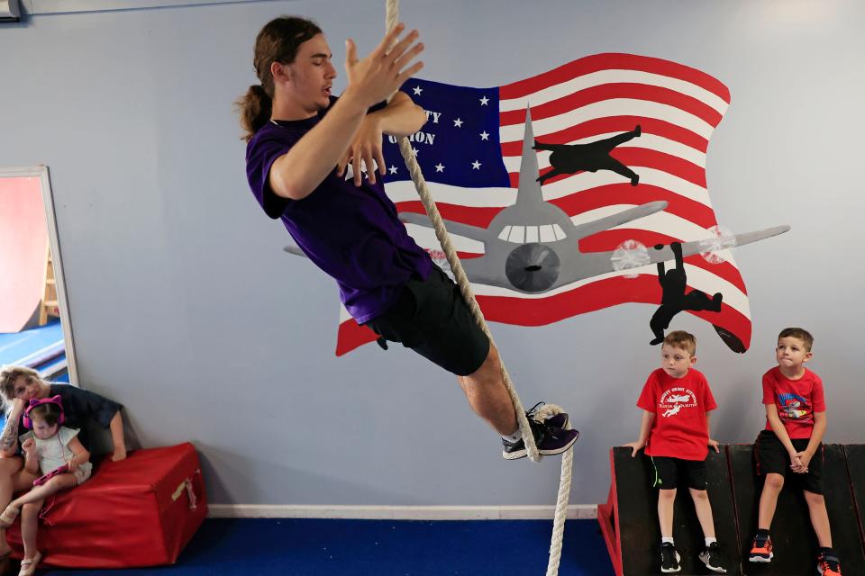 Alex Romer, 17, shows Lincoln Kusnerak and Maverick Meadows, both 6, the technique on rope climbing as Kaitlyn Nepper, left, and her daughter Maisie Meadows, 5, look on at Mighty Orion Fitness in Orange Park.