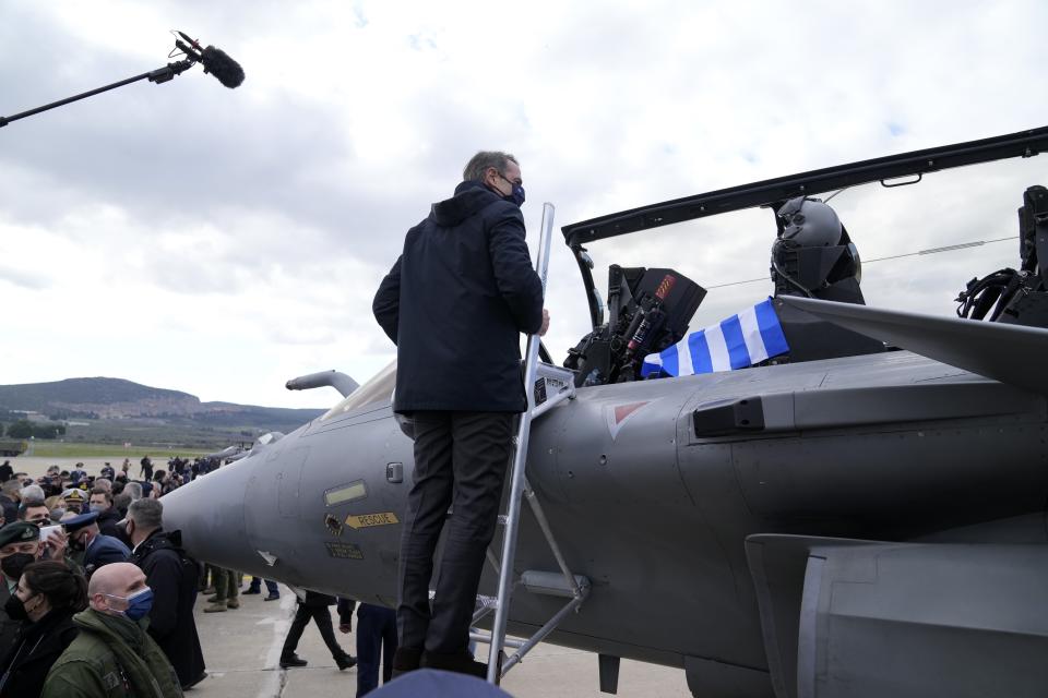 Greek Prime Minister Kyriakos Mitsotakis observes the cockpit of a Rafale fighter jet during a handover ceremony in Tanagra military air base, about 82 kilometres (51miles) north of Athens, Greece, on Wednesday, Jan. 19, 2022. Six advanced-tech Rafale jets bought from the French air force were handed over Wednesday to the Greek armed forces ‒ the first major delivery to result from multi-billion euro defense deals sealed with Paris last year. (AP Photo/Thanassis Stavrakis)