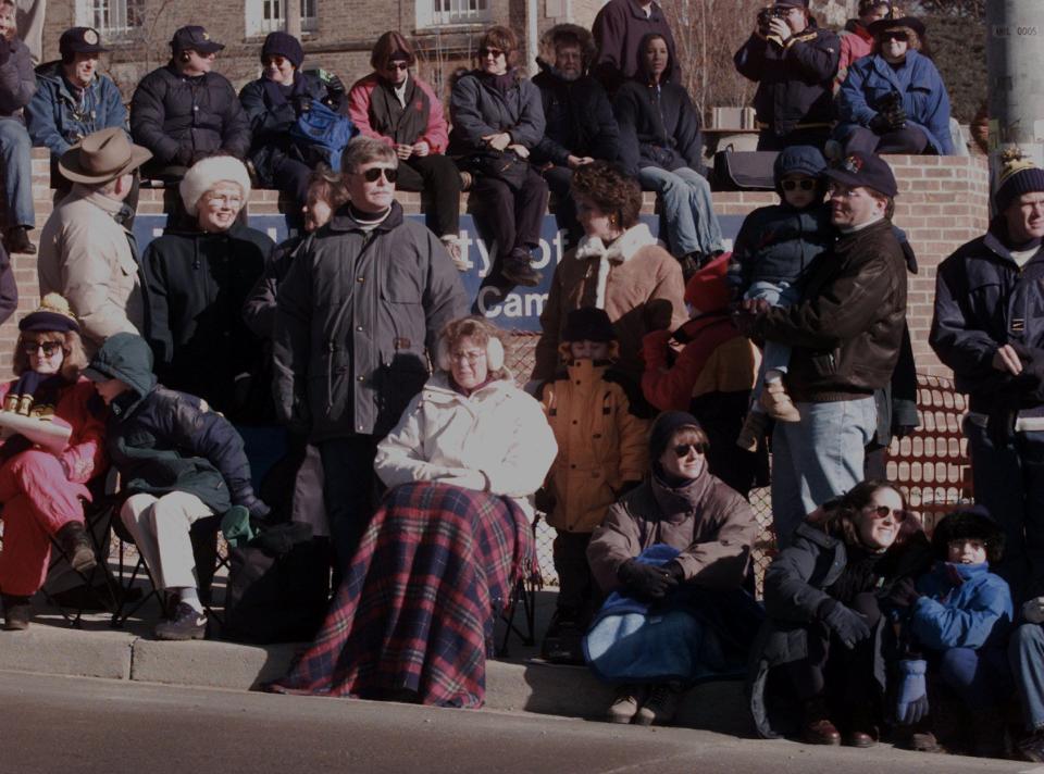 Some of the people in the crowd stay covered up as they wait on State St. for the beginning of the celebration parade for the University of Michigan football team in 1997 in Ann Arbor.