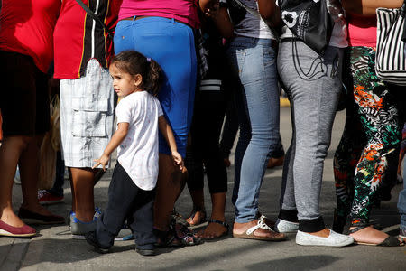 A girl stands next to her mother while they queue next to others to try to buy toilet paper and diapers outside a pharmacy in Caracas May 16, 2016. REUTERS/Carlos Garcia Rawlins