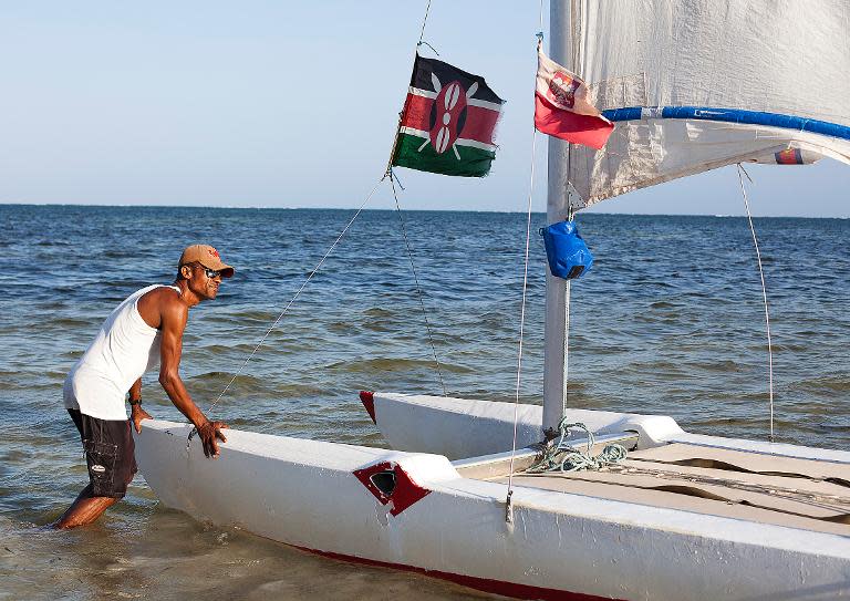 A man pushes his boat into the water looking for tourists to take sailing in the coastal city of Mombasa on February 22, 2014