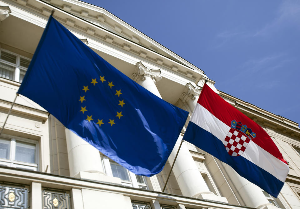 <p>Die EU- und Landesflagge am Parlamentsgebäude in Zagreb lässt nichts von der turbulenten Vergangenheit des Landes erahnen. Zwischen 1945 und 1991 war Kroatien eine Teilrepublik von Jugoslawien. 1991 stimmte eine große Mehrheit der Bevölkerung in einem Referendum für die Unabhängigkeit. Serbien versuchte daraufhin, verschiedene Landesteile wieder abzuspalten und an sich zu binden. Dieser Versuch sollte knapp vier Jahre dauern und als Kroatienkrieg in die Geschichte eingehen. (Bild: ASSOCIATED PRESS/AP Photo) </p>