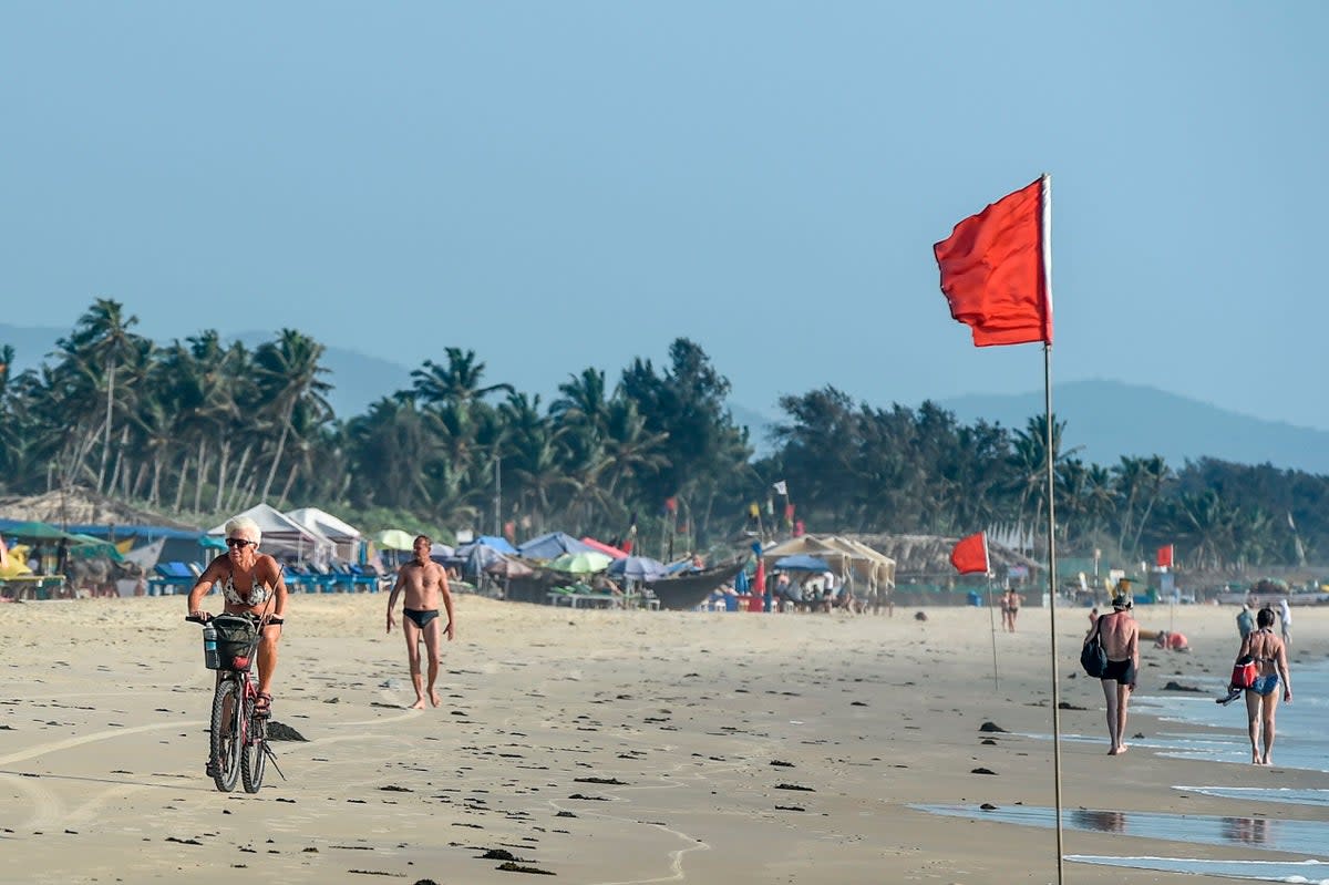 File: Foreigners enjoy walking and riding bikes on the beach in Goa on 13 March 2020 (AFP via Getty Images)