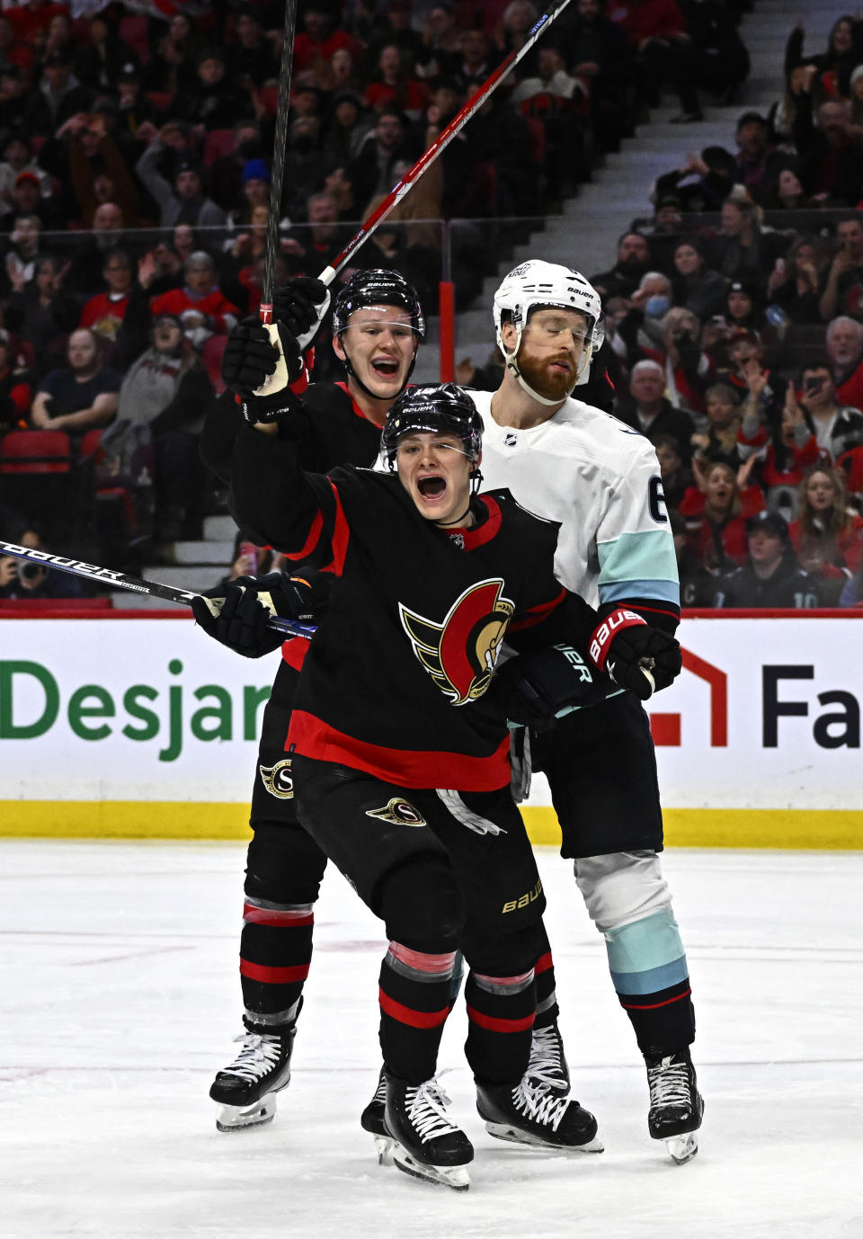 Ottawa Senators left wing Tim Stutzle (18) celebrates after his goal with left wing Brady Tkachuk (7) as Seattle Kraken defenseman Adam Larsson (6) skates away during second-period NHL hockey game action in Ottawa, Ontario, Saturday, Jan. 7, 2023. (Justin Tang/The Canadian Press via AP)