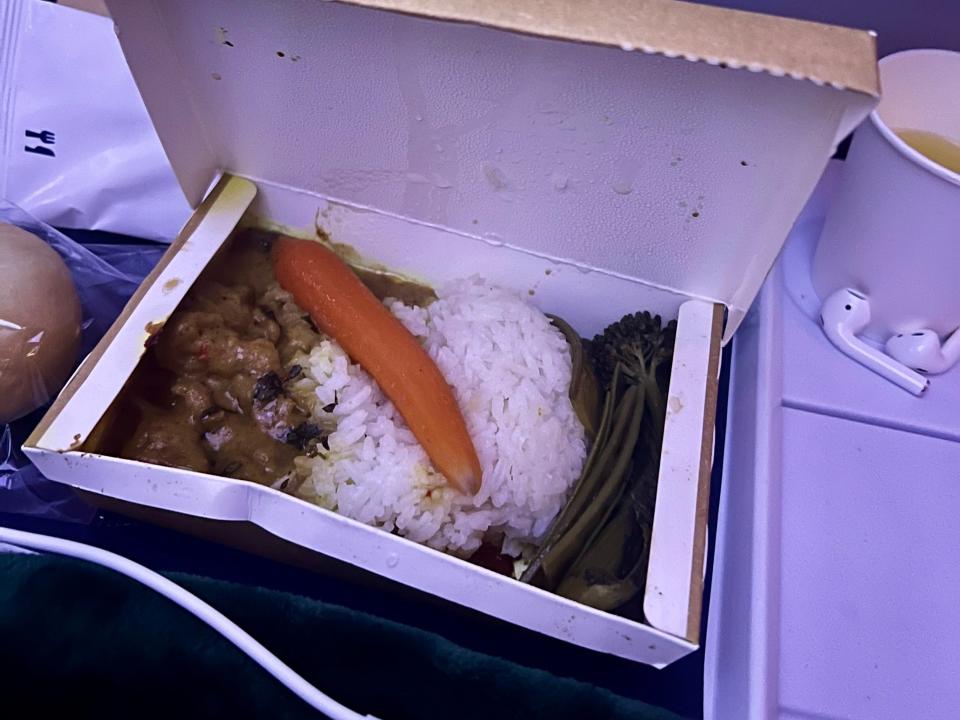 The dinner meal on the outbound with beef. rice, and veggies with a carrot on top.
