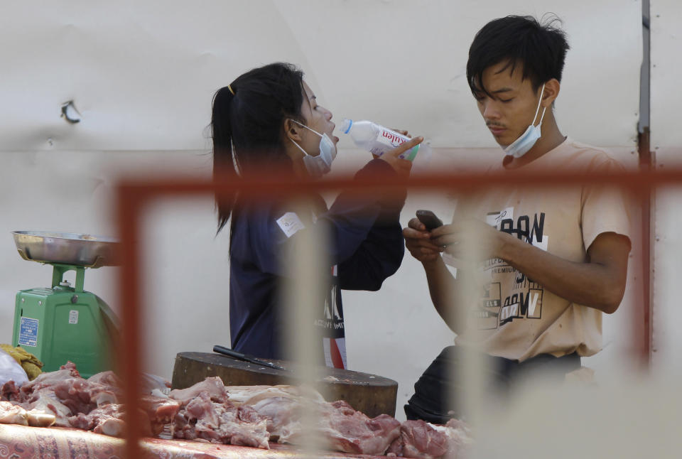 A couple of local vendors waits for customers as they sell pork meats at a motor-cart's mobile market in Phnom Penh, Cambodia, Sunday, April 25, 2021. The country's capital Phnom Penh has been locked down for two weeks from April 15, following a sharp rise in COVID-19 cases. (AP Photo/Heng Sinith)