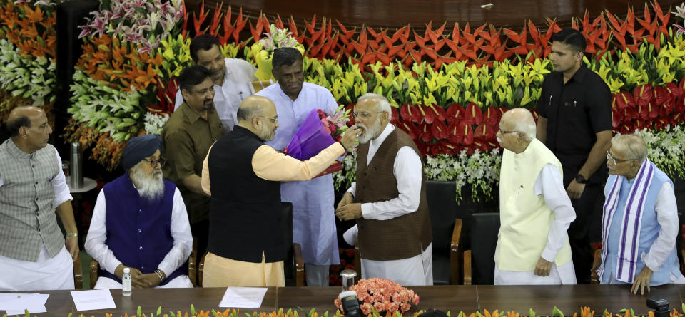 Bharatiya Janata Party (BJP) president Amit Shah, center left, offers sweets to Indian Prime Minister Narendra Modi after Modi elected ruling alliance leader, in New Delhi, India, Saturday, May 25, 2019. Shah announced Modi's name as the leader of the National Democratic Alliance in a meeting of the lawmakers in the Central Hall of Parliament in New Delhi, paving the way for Modi's second five-year term as prime minister after a thunderous victory in national elections. (AP Photo/Manish Swarup)