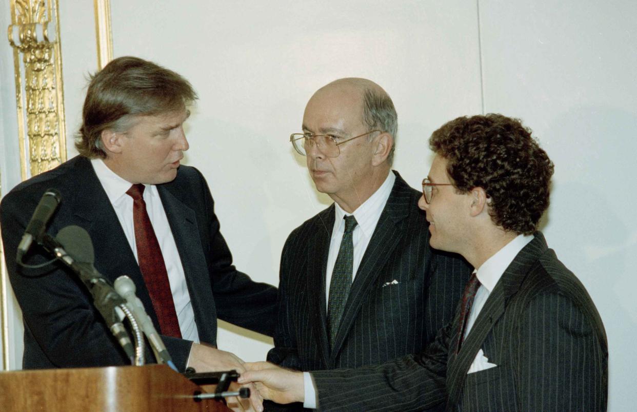 Donald Trump shakes hands with Robert Miller while patting Wilbur Ross on the back during a press conference, on Nov. 16, 1990, announcing a deal over control of Trump's troubled Taj Mahal Casino under bankruptcy court protection and will give investors a 50 per cent stake in it while Trump remains chairman. Miller is an attorney and Ross in financial adviser for the bondholders.
