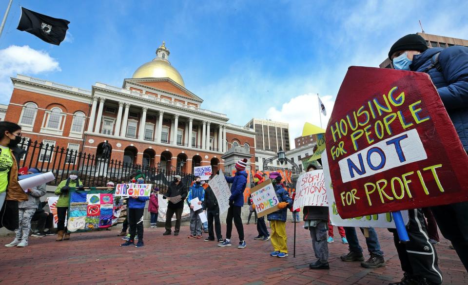 People hold signs in front of a state capitol building