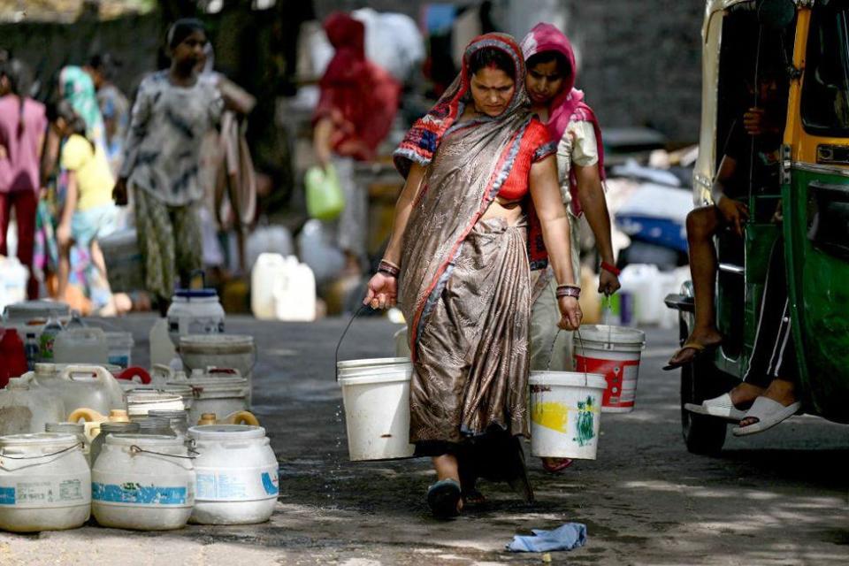 Residents carry water containers after filling them from a municipal tanker in a low-income neighbourhood in Delhi on May 30, 2024