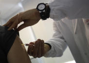 FILE - In this Feb. 23, 2018, file photo, doctor Roberto Ieraci vaccinate a woman in a vaccine center in Rome. Last spring, as false claims about vaccine safety threatened to undermine the world's response to COVID-19, researchers at Facebook wrote that they could reduce vaccine misinformation by tweaking how vaccine posts show up on users' newsfeeds, or by turning off comments entirely. Yet despite internal documents showing these changes worked, Facebook was slow to take action. (AP Photo/Alessandra Tarantino, File)