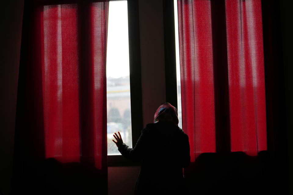 Pakistani-born Iram Aslam, 29, peeks through the window of a local social activities center in Guastalla, northern Italy, Saturday, Feb. 11, 2023, during an interview with The Associated Press. She recounted how she angered her family by refusing a marriage, decided at her birth, to a cousin in Pakistan. Courageous refusal by young immigrant women in Italy to submit to forced marriages sometimes carries a deadly price. In two murder trials this month, Italian prosecutors are seeking justice for Pakistani immigrant women allegedly killed because they refused marriages imposed by their parents. (AP Photo/Luca Bruno)