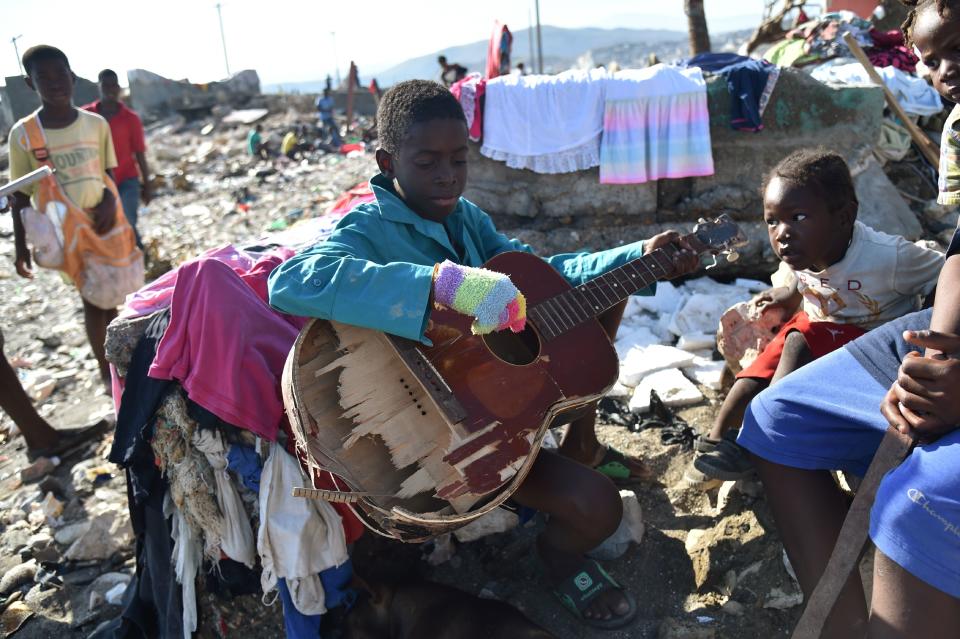 A boy plays with a broken guitar while sitting in rubble on Oct. 8, 2016.&nbsp;