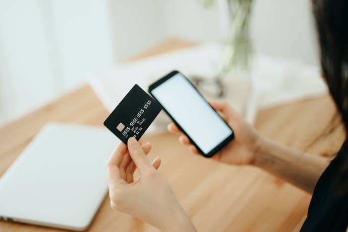 A woman holding a cellphone and a credit card