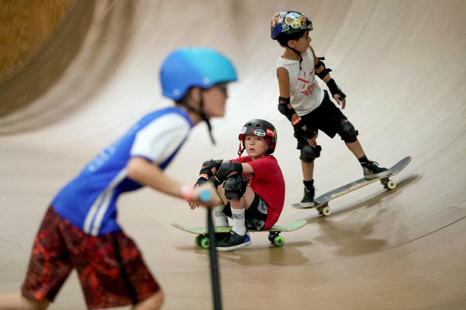 Eliot Reavis, 10, of Detroit, left, and Kole Alberts, 8, of Frankenmuth, skate by Danie Laduke, 10, of Ortonville, as he takes a break on his board during the skate clinic held at Modern Skate Park on Monday, July 10, 2023.