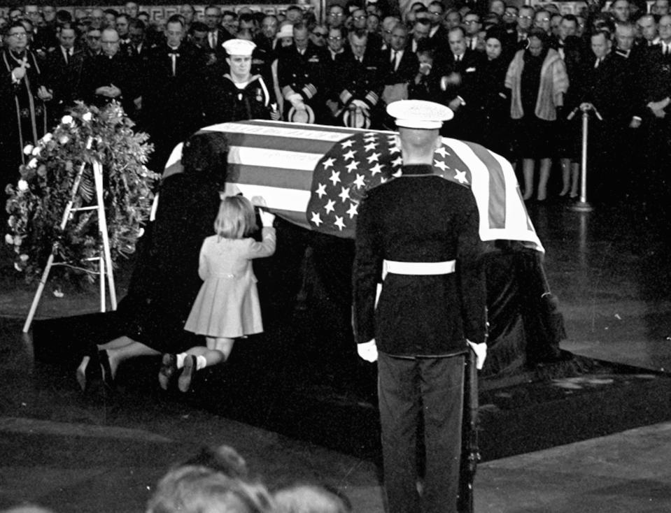 Mrs. John F. Kennedy kisses the casket of her husband in the rotunda of the U.S. Capitol on Nov. 24, 1963. Daughter Caroline kneels alongside.