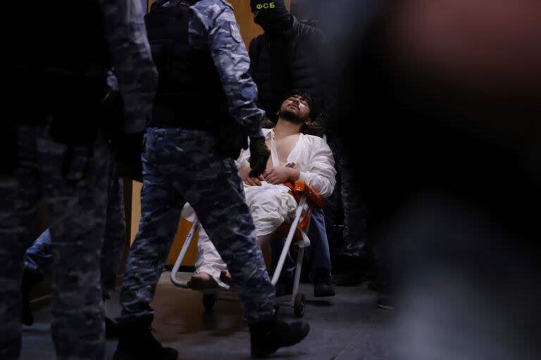 Un hombre sospechoso de participar en el ataque a una sala de conciertos que dejó 137 personas muertas es escoltado por agentes rusos antes de su audiencia de detención preventiva en el Tribunal del Distrito de Basmanny en Moscú el 25 de marzo de 2024. 