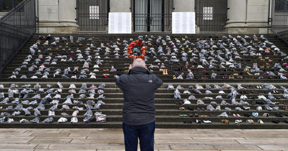 A passerby stops to take pictures of the annual women's shoe memorial set up on the steps of the Art Gallery in Vancouver, British Columbia December 6, 2012. The memorial, consisting of several hundred pairs of shoes in memory of all missing and murdered women in Canada, is displayed annually on the anniversary of the Montreal Ecole Polytechnique massacre that took place in 1989. REUTERS/Andy Clark (CANADA - Tags: SOCIETY CRIME LAW ANNIVERSARY)
