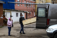 Ramilya Shigalturina stands in the courtyard of a morgue at Infectious Hospital No. 5 in Nizhny Novgorod, Russia, Wednesday, on Oct. 20, 2021, as a worker moves a coffin containing the body of her grandmother, who died of COVID-19. Shigalturina said the disease was “really dreadful and dangerous,” and she begged Russians to get vaccinated. The resident of Nizhny Novgorod, the country's fifth-largest city, said her 83-year-old grandmother, who was unvaccinated, “died right away after catching it.” (AP Photo/Roman Yarovitcyn)