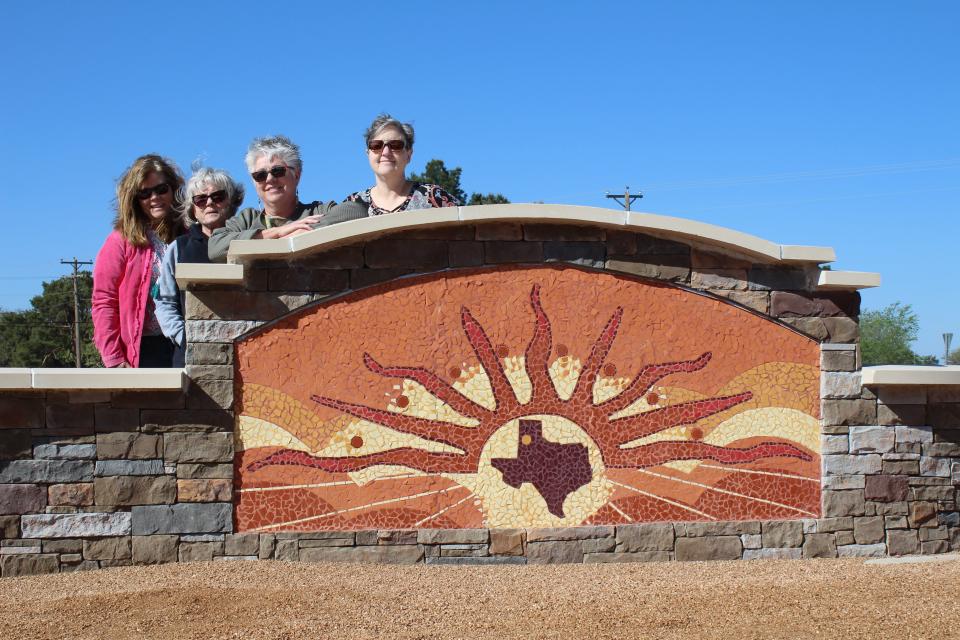 From left, Shelley Carver, Nell Elston, artist Pauline Mills and Kelly Reynolds pose with Levelland's new mosaic highway monument on Monday in Levelland.