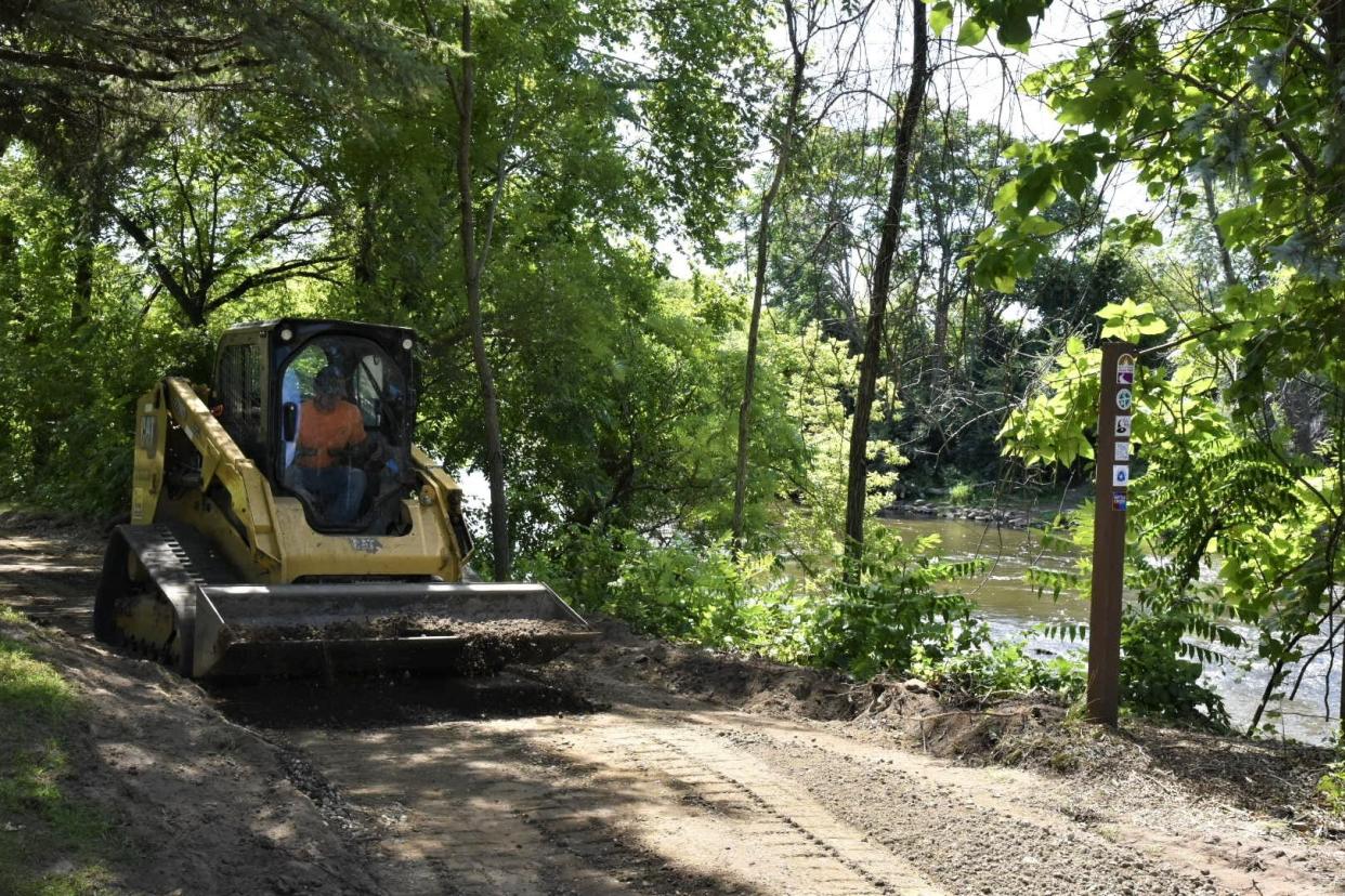 A worker with Hunter-Prell Co. smooths out the ground after pavement was removed in parts of Linear Park Pathway along the North Branch of the Kalamazoo River on Friday, Aug. 12, 2022 in Battle Creek.