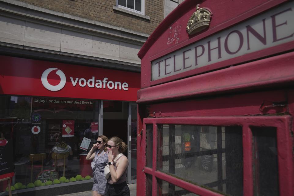 People walk past a Vodafone store in London, Wednesday, June 14, 2023. Vodafone and Three, which is owned by Hong Kong's CK Hutchison agreed Wednesday to merge their U.K. businesses in order to capitalize on the rollout of the next generation of wireless technology. (AP Photo/Kin Cheung)