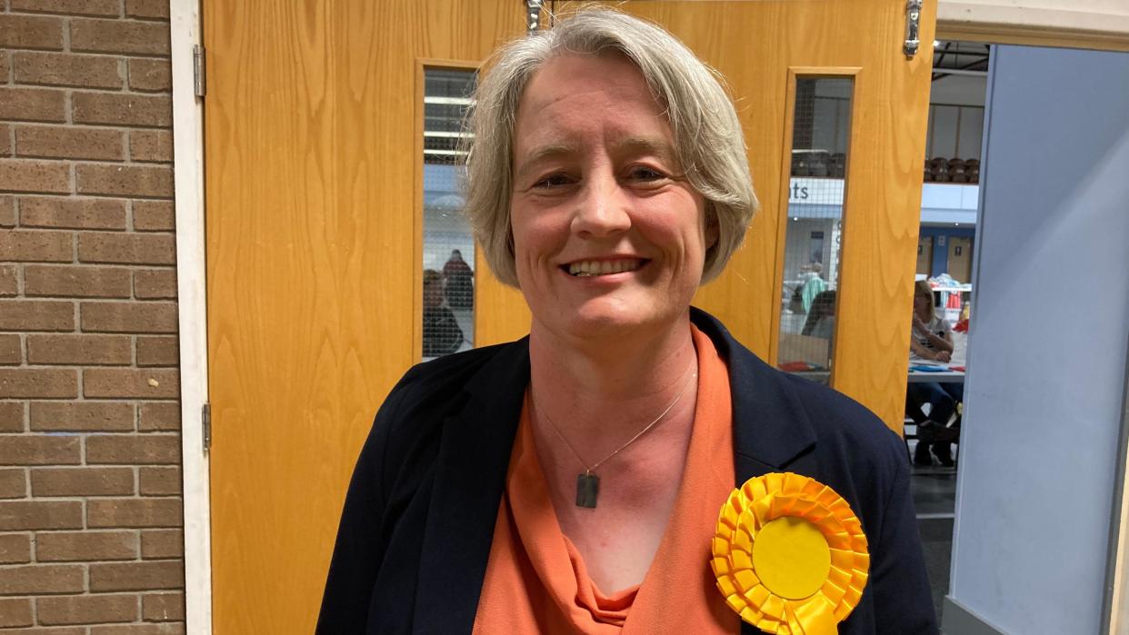 Claire Young smiling while wearing an orange rosette