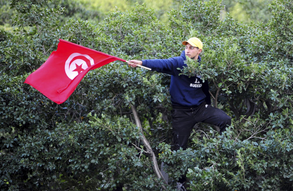 A man waves a Tunisian flag during a protest against Tunisian President Kais Saied in downtown Tunis, Tunisia, Saturday Jan. 14, 2023. Tunisians mark 12 years since Tunisian protesters unleashed Arab Spring uprisings around the region. The protest comes after disastrous parliamentary elections last month in which just 11% of voters cast ballots. It also comes as the country is going through a major economic crisis, with inflation and joblessness on the rise. (AP Photo/Hassene Dridi)