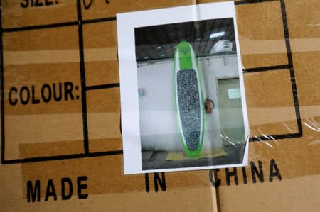 A Doyle surfboard manufactured in China are shown in its shipping box in a warehouse in Lake Forest, California