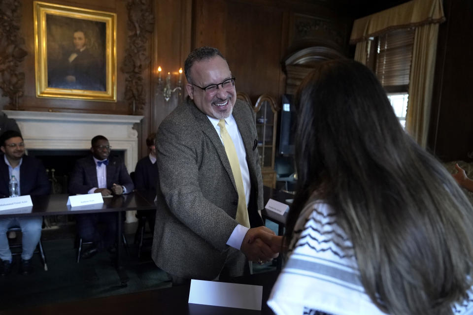 U.S. Education Secretary Miguel Cardona, center, greets Dartmouth College student Yasmine Abouali, of Palestinian Tunisian heritage, right, at the start of a roundtable discussion, Wednesday, Jan. 10, 2024, on the Dartmouth College campus, in Hanover, N.H. Fallout from the Israel-Hamas war has roiled campuses across the U.S. and reignited a debate over free speech. (AP Photo/Steven Senne)