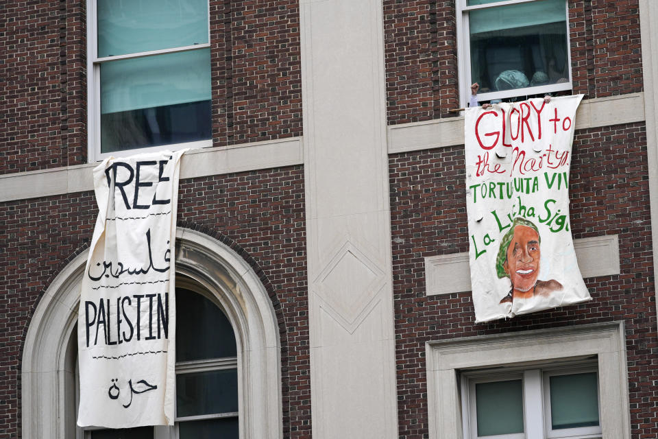 FILE - A demonstrator pumps his fist as he hangs a sign from a window in Hamilton Hall inside the Columbia University campus, Tuesday, April 30, 2024, in New York. (AP Photo/Mary Altaffer, File)