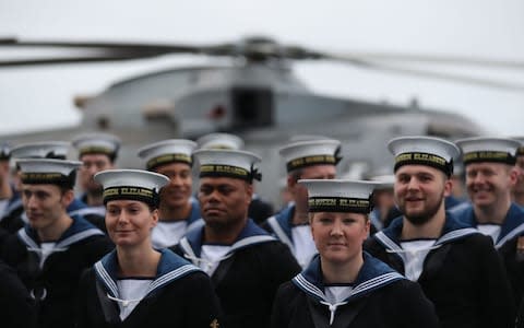 Members of the crew of HMS Queen Elizabeth, the UK's newest aircraft carrier, muster on the deck ahead of the ship's arrival in Portsmouth - Credit: Andrew Matthews/PA
