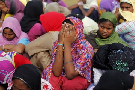 A Rohingya migrant woman, who arrived with others in Indonesia by boat, covers her face as she waits for breakfast inside a temporary compound for refugee in Kuala Cangkoi village in Lhoksukon, Indonesia's Aceh Province May 17, 2015. REUTERS/Beawiharta