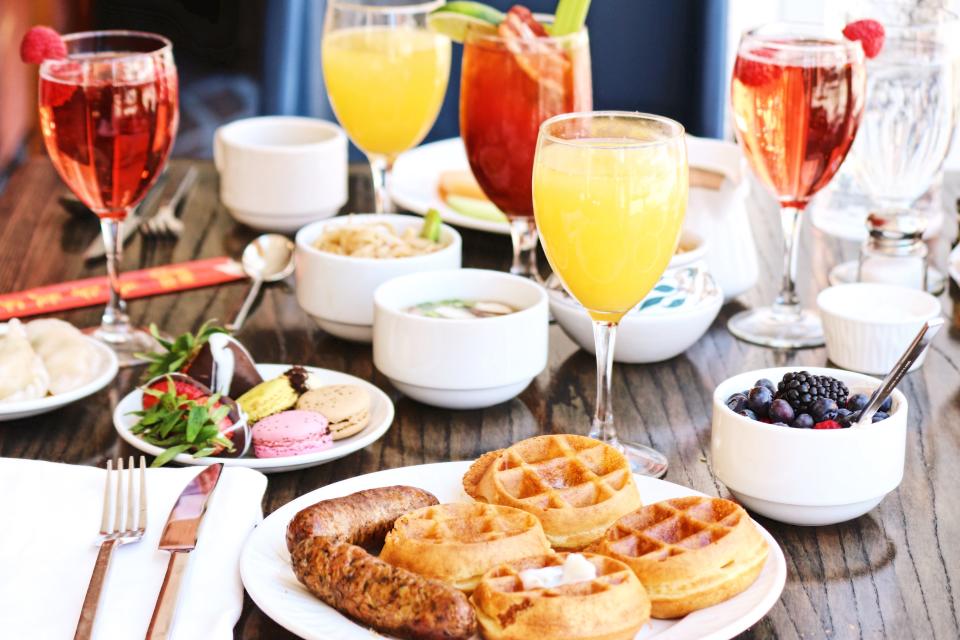 A brunch spread including mimosas, waffles, and fruit.