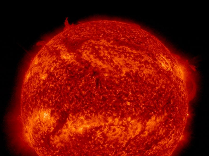 video shows sun rotating ball of red plasma with a filament emerging from the top then breaking away and swirling around the north pole