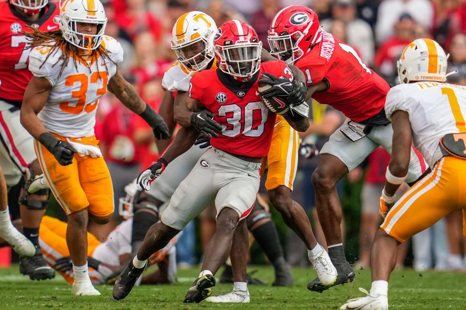 Georgia running back Daijun Edwards (30) tries to break a tackle from Tennessee defensive back Brandon Turnage (8) during their 2022 game at Sanford Stadium.