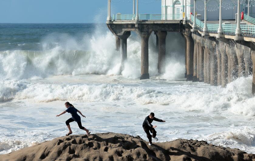 Manhattan Beach, California December 30, 2023-Children scramble as waves come crashing on shore next to the Manhattan Beach Pier Saturday. (Wally Skalij/Los Angeles Times)