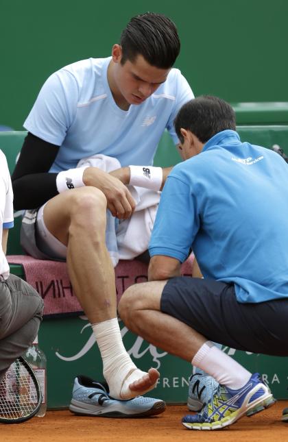 Milos Raonic of Canada receives medical treatment during the quarterfinal match against Tomas Berdych of Czech Republic at the Monte Carlo Tennis Masters tournament in Monaco, Friday April 17, 2015. Tomas Berdych advanced to the semifinals of the Monte Carlo Masters after Milos Raonic retired with a foot injury. (AP Photo/Lionel Cironneau)