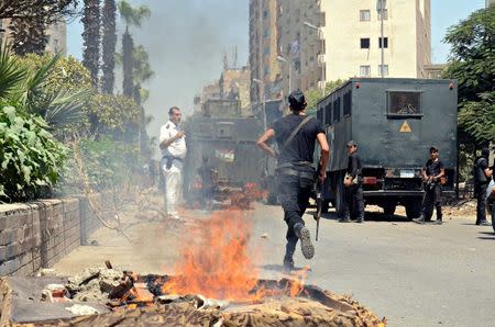 Police take positions after a protest was dispersed quickly, leaving fire burning in a main street in Giza, south of Cairo August 14, 2014. REUTERS/Al Youm Al Saabi Newspaper