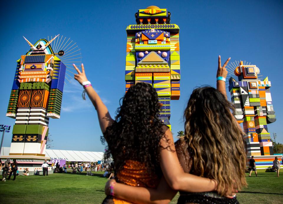 Safdari Zaidi (left) and Jacky Garcia of Los Angeles pose for a photo in front of "The Messengers" by Kumkum Fernando during the Coachella Valley Music and Arts Festival at the Empire Polo Club in Indio, Calif., Friday, April 14, 2023.