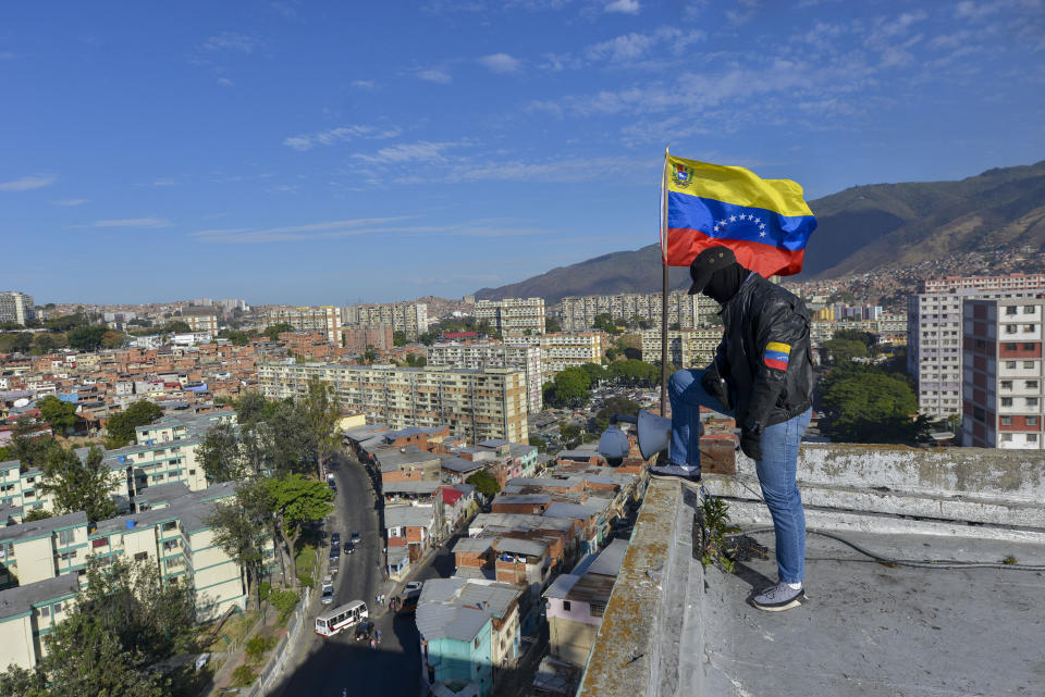 A member of a pro-government militia group stands on a roof overlooking the 23 de Enero neighborhood during an invasion drill in Caracas, Venezuela, Saturday, Feb. 15, 2020. Venezuela's President Nicolas Maduro ordered two days of nationwide military exercises, including participation of civilian militias. (AP Photo/Matias Delacroix)