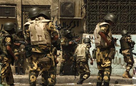 Riot police and soldiers from the army take up positions during clashes with stone-throwing members of the Muslim Brotherhood and supporters of ousted Egyptian President Mohamed Mursi around the area of Rabaa Adawiya square, where the protesters are camping, in Cairo in this August 14, 2013 file photo. REUTERS/Asmaa Waguih/Files