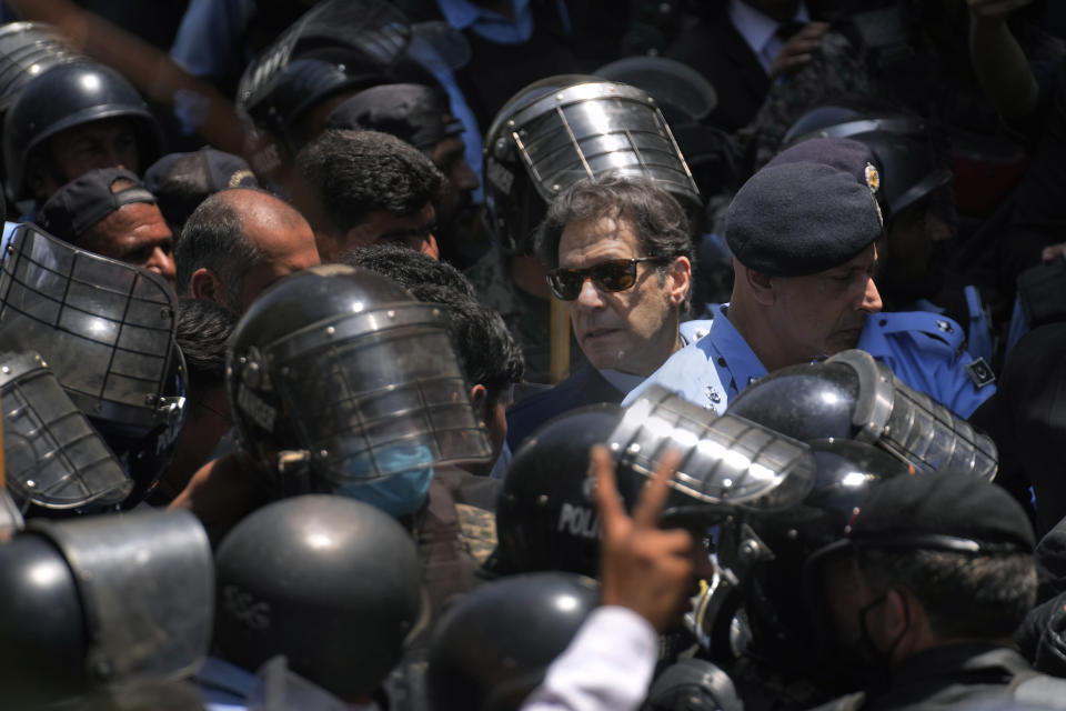 Pakistan's former Prime Minister Imran Khan, center, is escorted by police officers as he arrives to appear in a court, in Islamabad, Pakistan, Friday, May 12, 2023. A high court in Islamabad has granted Khan a two-week reprieve from arrest in a graft case and granted him bail on the charge. (AP Photo/Anjum Naveed)