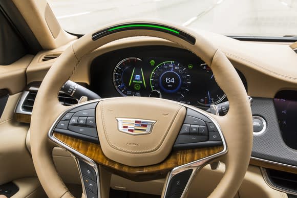 A view of a Cadillac CT6's steering wheel and instrument cluster, showing the Super Cruise light in the wheel's rim.