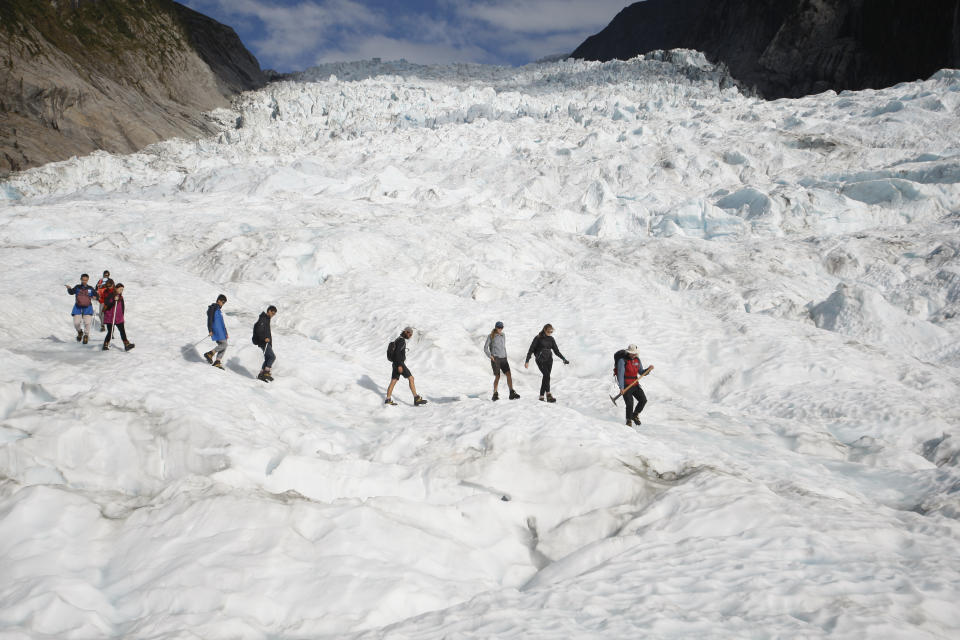 FILE - In this Feb. 6, 2016, file photo, tourists who have taken a helicopter trip onto the Fox Glacier follow a guide in New Zealand. New Zealand lawmakers have joined together across the aisle to pass a bill aimed at combating climate change. The Zero Carbon bill aims to make New Zealand reduce its greenhouse gas emissions to the point the country becomes mostly carbon neutral by 2050. (AP Photo/Nick Perry, File)